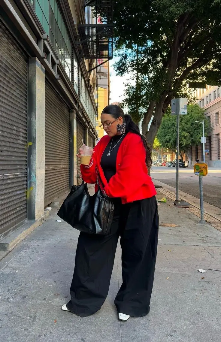curvy woman in red bomber jacket black turtleneck wide leg black trousers white pointed shoes large black tote bag street style outfit 1