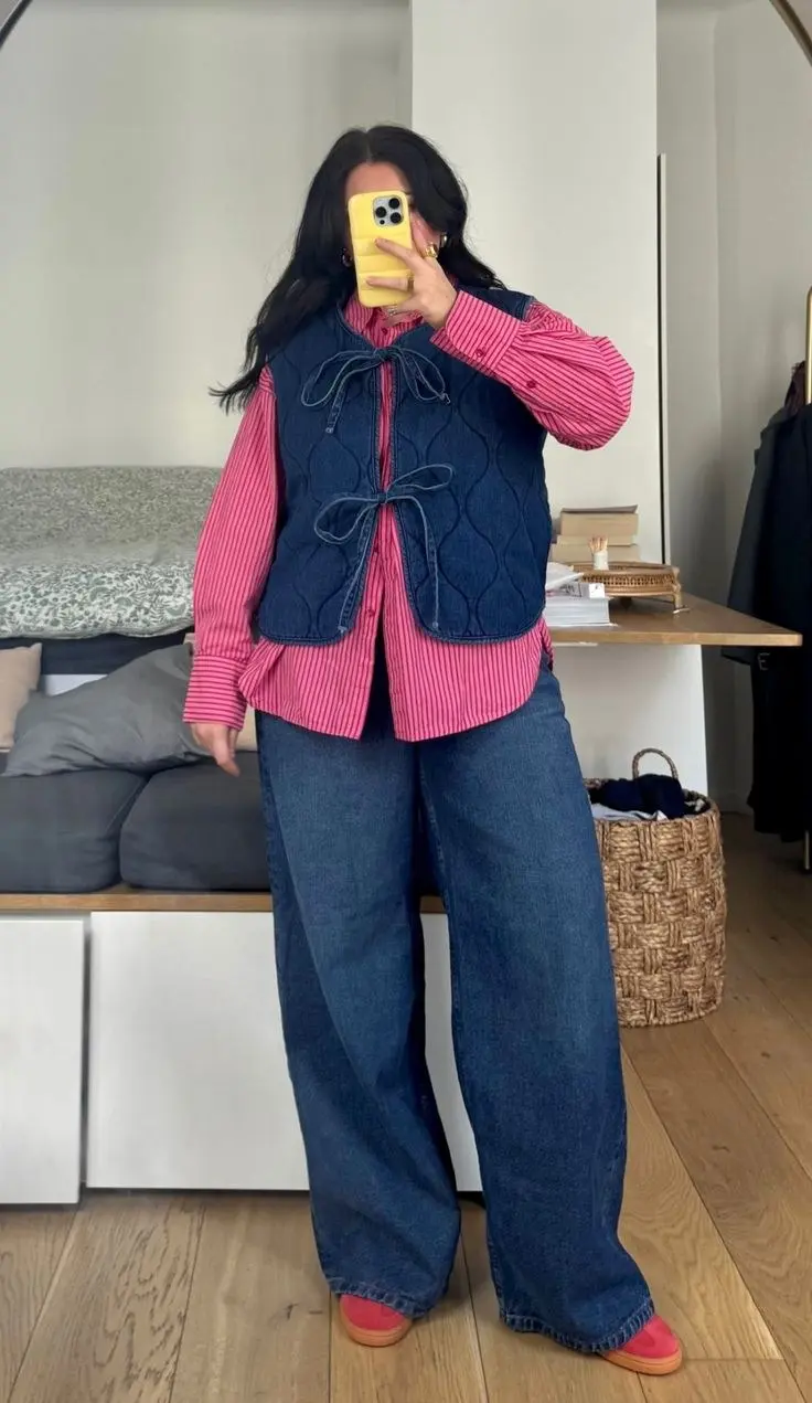 curvy woman in pink striped shirt navy quilted denim tie-front vest wide leg dark denim jeans coral sneakers mirror selfie outfit 3