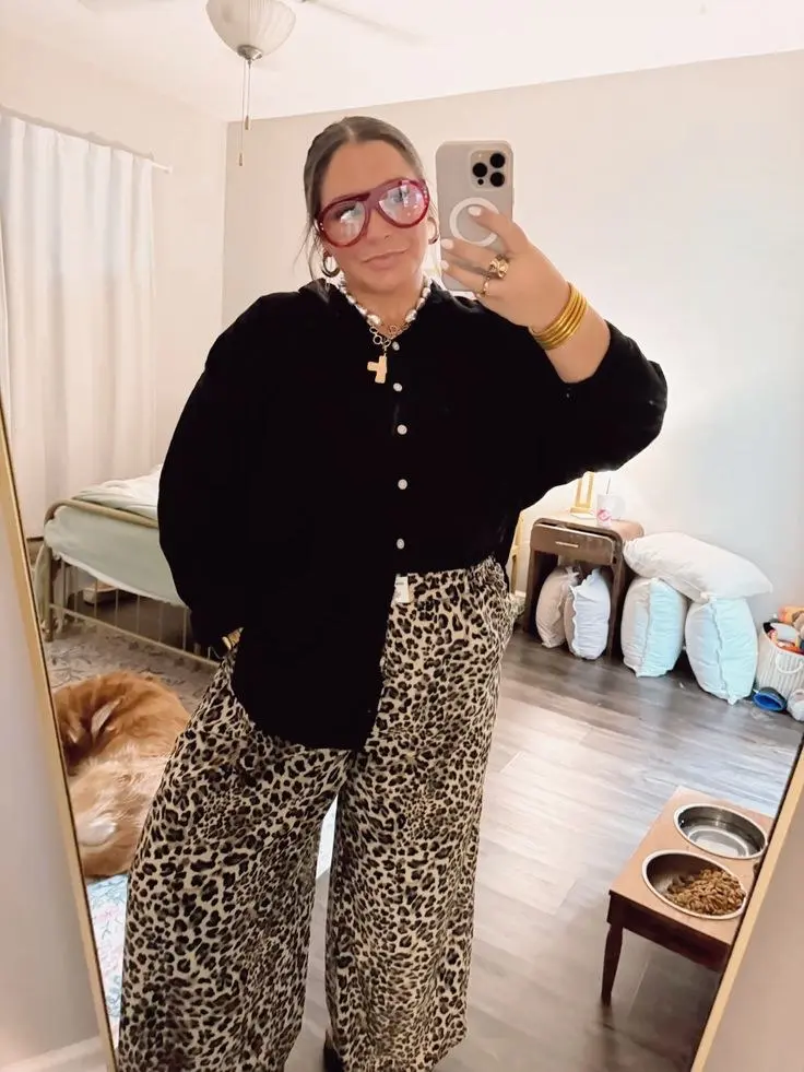 curvy woman in black oversized button cardigan leopard wide leg trousers red framed glasses gold bangles pearl charm necklace mirror selfie outfit 5