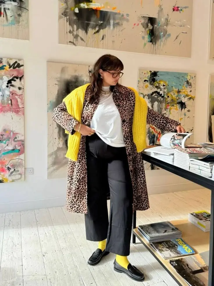curvy woman in long leopard print coat yellow chunky knit cardigan white turtleneck black wide leg trousers black loafers yellow socks art gallery outfit 7