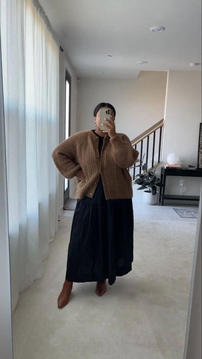 curvy woman in camel chunky oversized cardigan black long tiered midi dress cognac block heel ankle boots mirror selfie indoor outfit 14