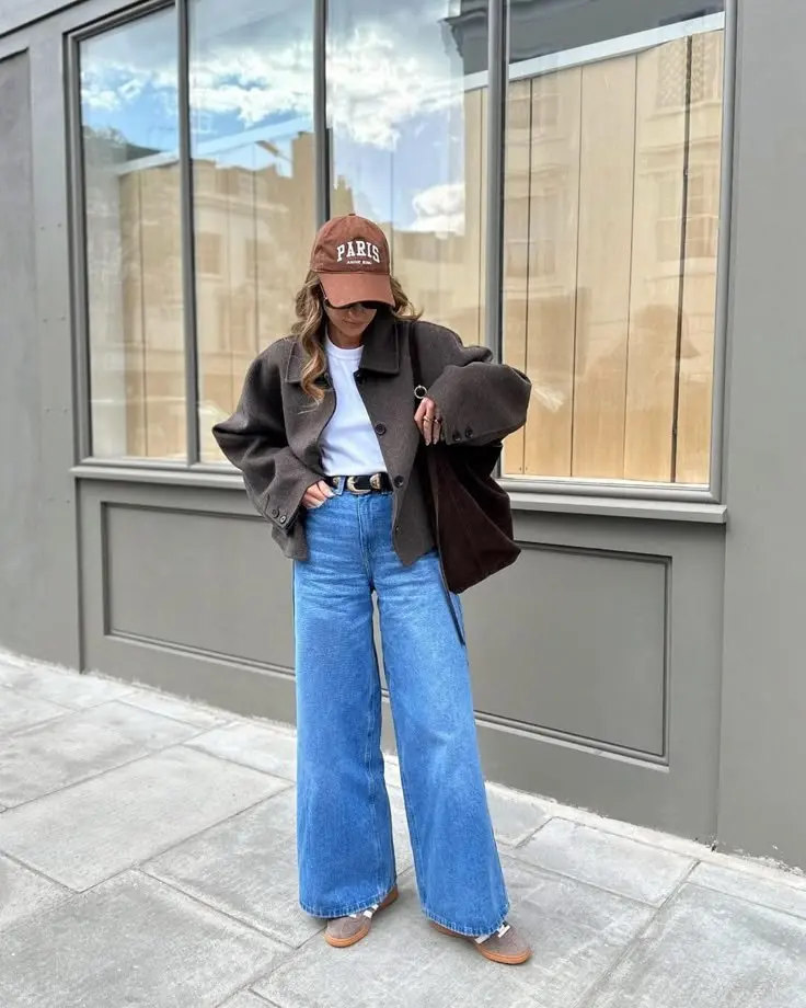woman in charcoal structured wool jacket white tee light blue wide leg jeans camel loafers brown baseball cap dark bag street outfit 13