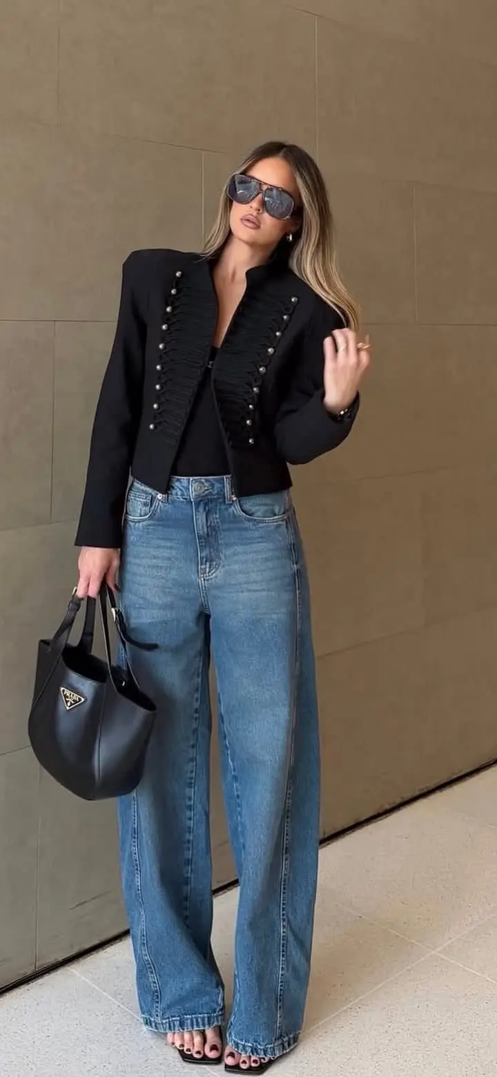 woman in black military style button trim blazer black bodysuit light blue wide leg jeans black strappy heeled sandals black bucket bag large sunglasses outfit 18