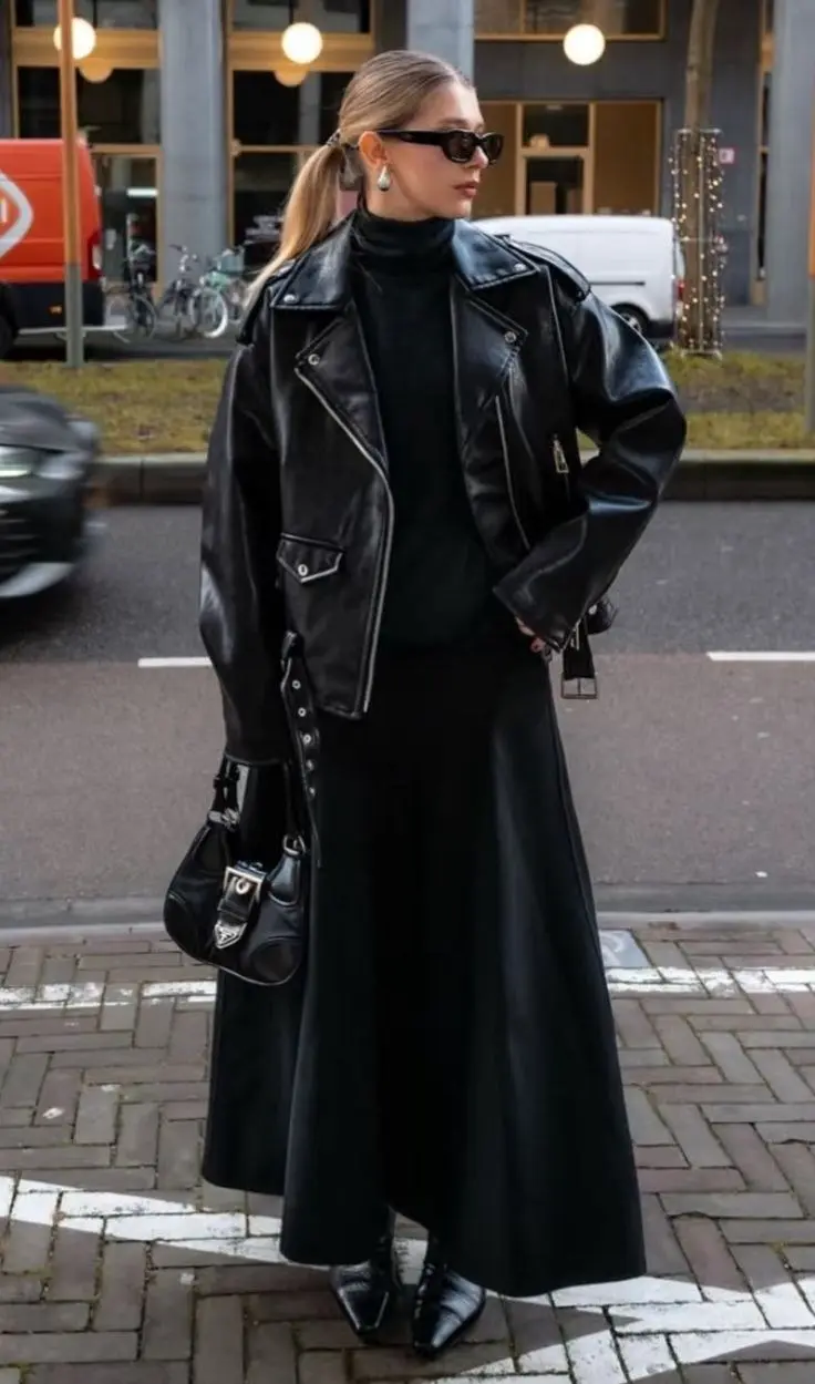 woman in oversized black moto leather jacket black turtleneck black floor length maxi skirt pointed croc boots small patent black shoulder bag drop earrings sunglasses street outfit 8