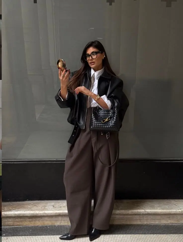 woman in black leather bomber jacket white button down shirt rust brown tie brown pinstripe wide leg trousers black shoulder bag glasses mirror selfie outfit 18