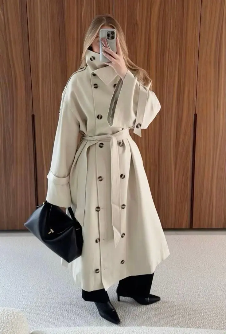 woman in mirror selfie wearing cream structured belted long trench coat black turtleneck black wide leg trousers black kitten heel ankle boots black leather tote bag outfit 6