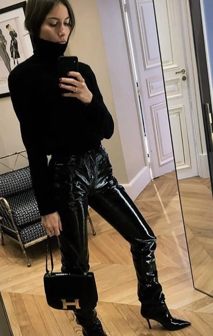 woman in mirror selfie wearing black turtleneck, black patent leather pants, black pointed stiletto boots, holding small black Hermes bag with gold H clasp, outfit 2