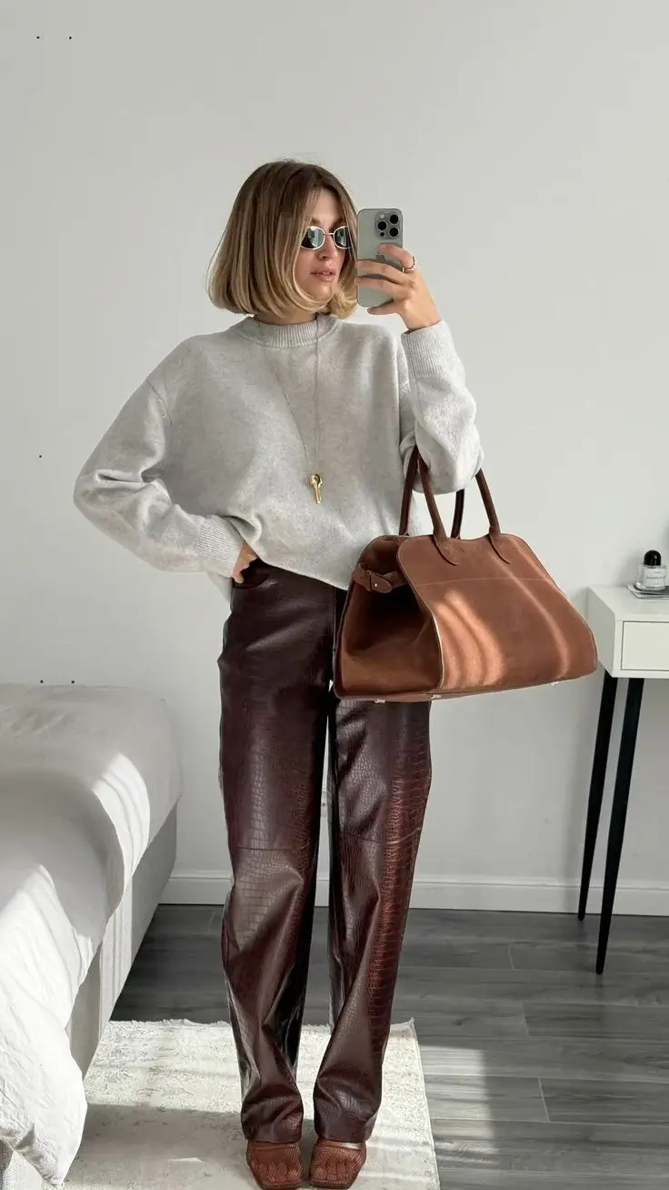 woman mirror selfie wearing oatmeal cream oversized sweater, gold pendant necklace, chocolate brown croc-embossed wide leg leather pants, brown loafers, tan large leather tote bag, oval tinted sunglasses, outfit 16