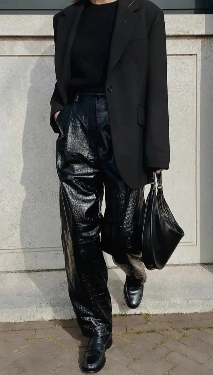 person wearing oversized black single-button blazer, black ribbed fitted top, black croc patent high-gloss wide leg leather pants, chunky black loafers, black soft hobo bag, minimal accessories, outfit 17