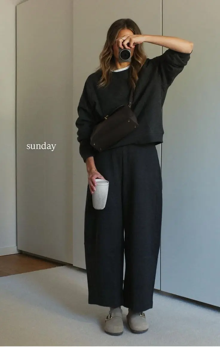 woman in charcoal sweatshirt and wide leg dark knit trousers with brown belt bag and taupe suede mules mirror selfie outfit 1