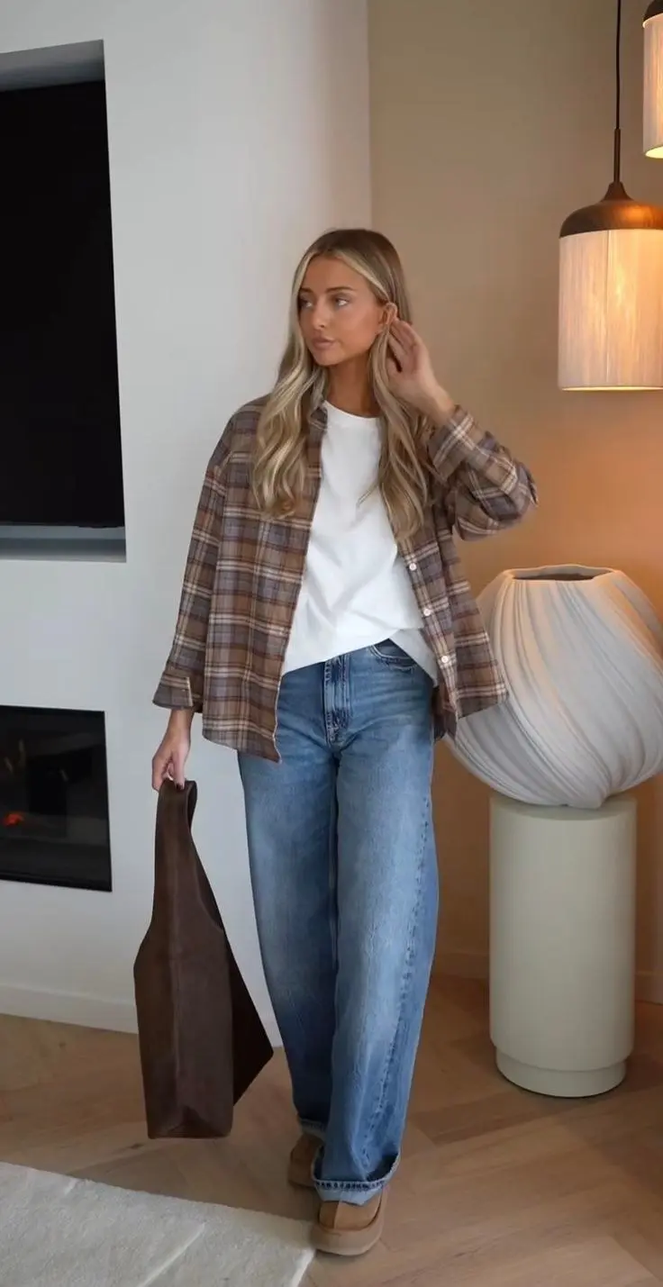 woman in brown plaid flannel open shirt white tee medium wash wide leg jeans dark tote platform tan sneakers indoor outfit 5