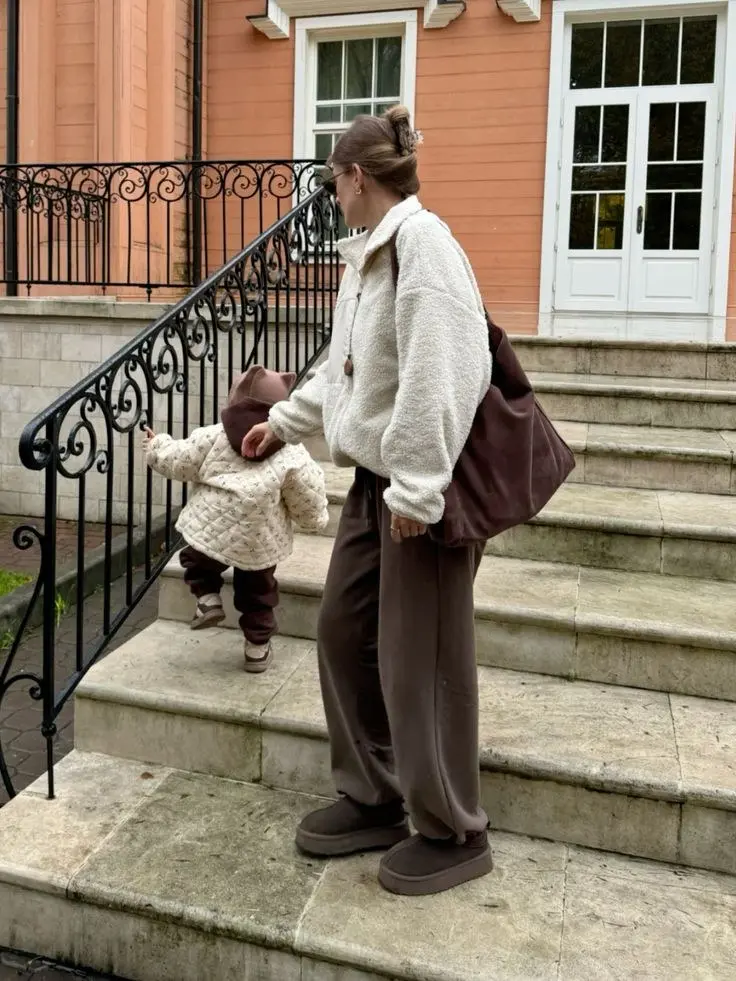 woman with toddler on outdoor steps in cream sherpa half-zip wide chocolate brown trousers chunky boots large burgundy shoulder bag claw clip outfit 6