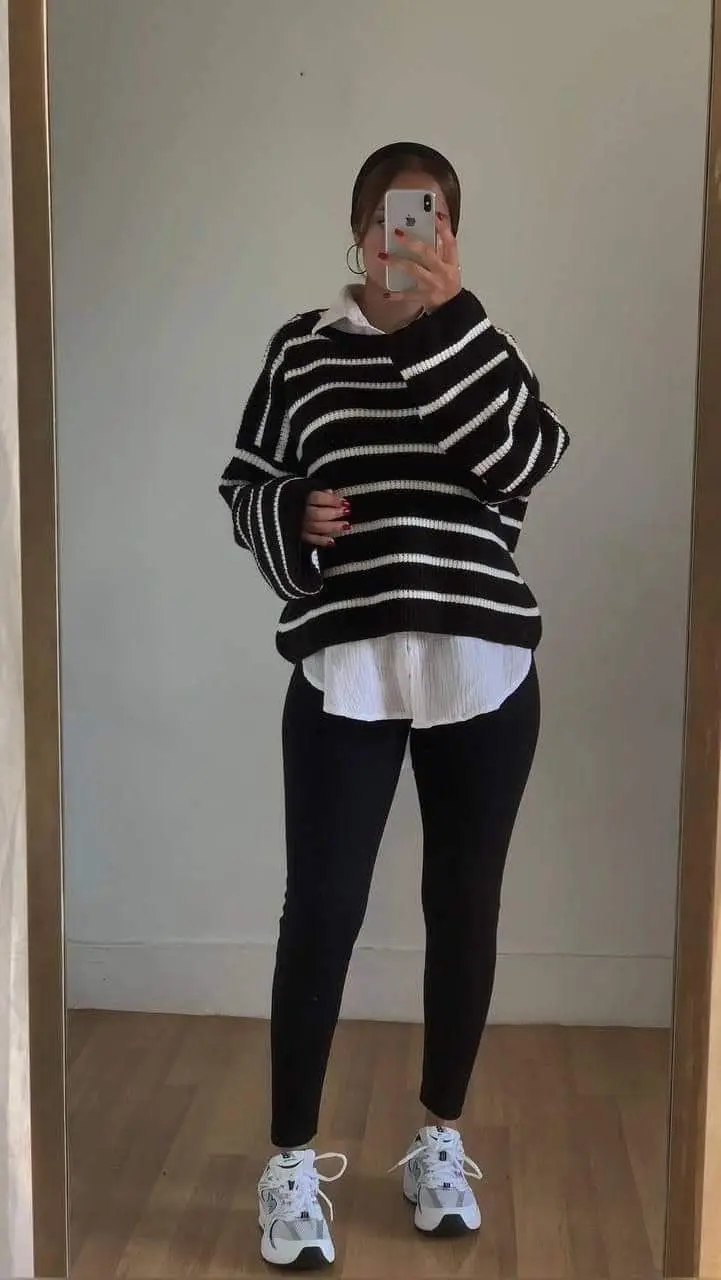 woman in black and white striped oversized sweater over white button down shirt black leggings white New Balance sneakers gold hoop earrings mirror selfie outfit 12