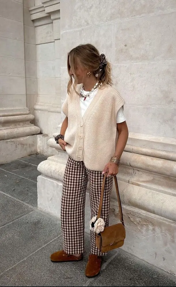 woman outdoors in cream button front knit vest white tee brown white gingham wide trousers caramel suede ankle boots pearl chain necklace leopard scrunchie caramel bag outfit 25
