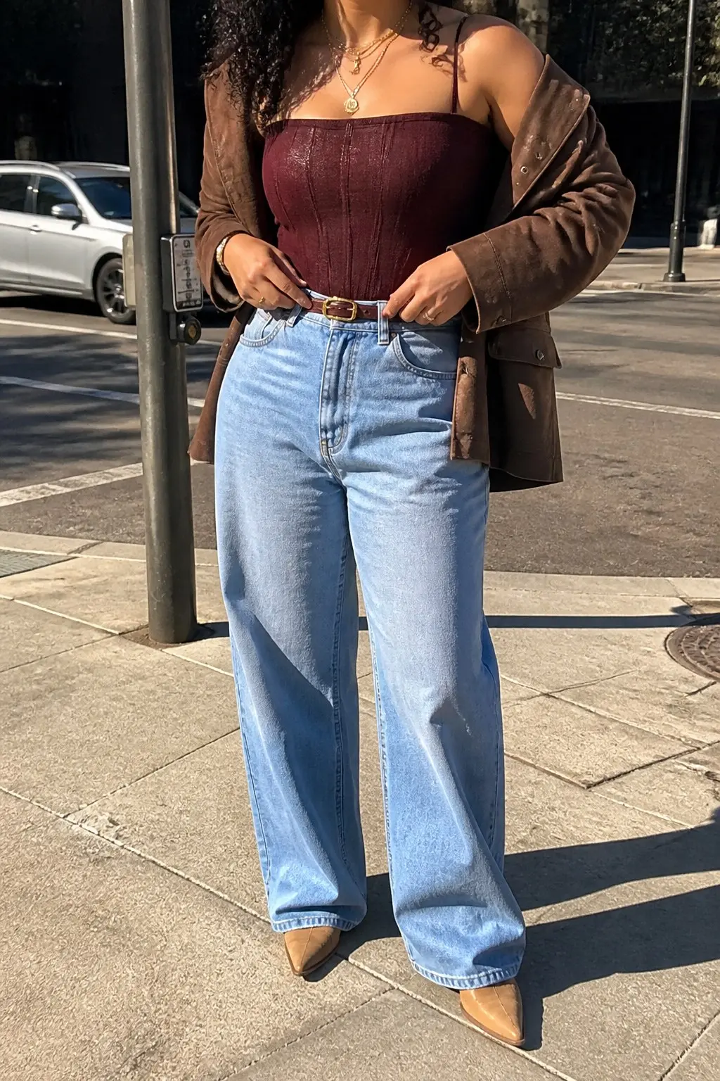 brown suede jacket worn off shoulders burgundy corset top light wash wide leg jeans tan leather belt camel cowboy ankle boots gold layered necklace outfit 6