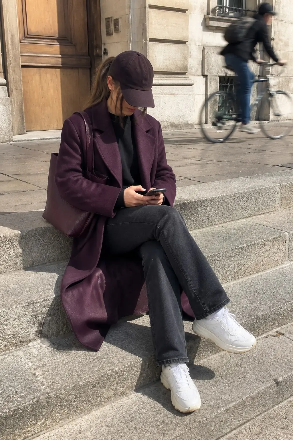 long plum wool coat over black crewneck sweatshirt dark gray wide-leg jeans chunky white platform sneakers plum baseball cap and plum leather tote outfit 25