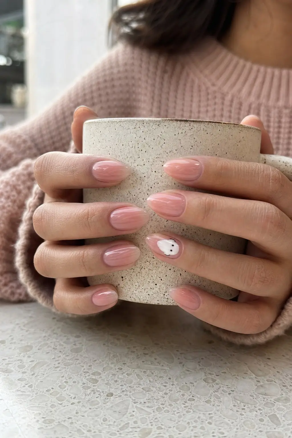 medium almond nails with translucent jelly pink gel base, white ghost with black eyes on ring finger accent nail, sheer glossy finish, nail look 3