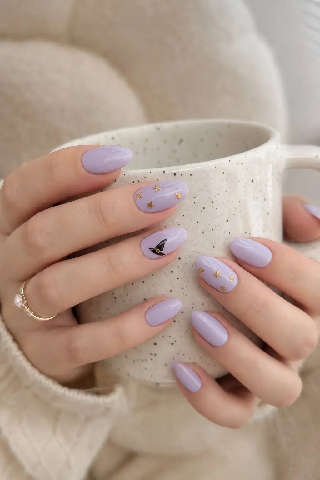 medium almond nails with soft lavender gel base, black witch hat with gold band on one accent nail, tiny gold star details scattered on other nails, nail look 13