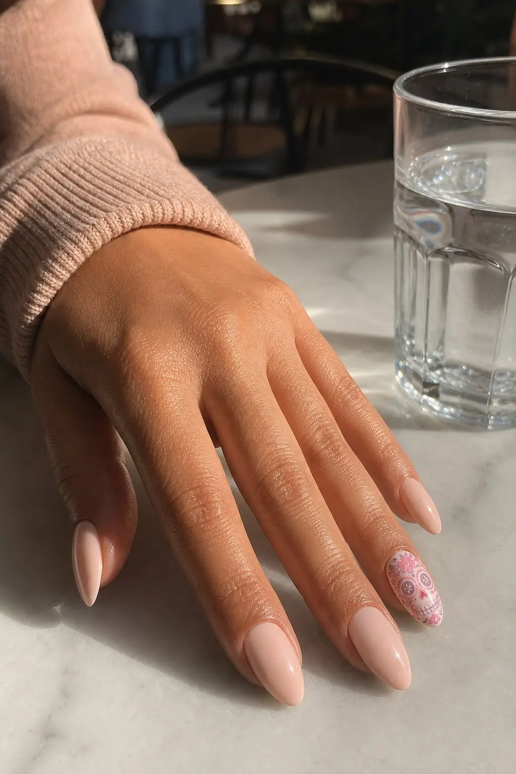 medium almond nails with peach nude cream gel base, ring finger accent nail with white base and pink sugar skull painted with floral details, nail look 18
