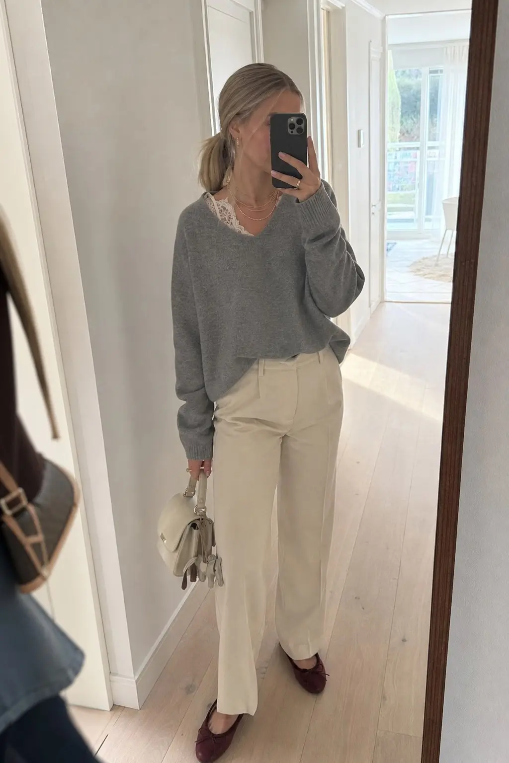grey v-neck sweater white lace trim visible at neckline cream straight leg trousers burgundy ballet flats cream structured top handle bag gold chain necklace outfit 9