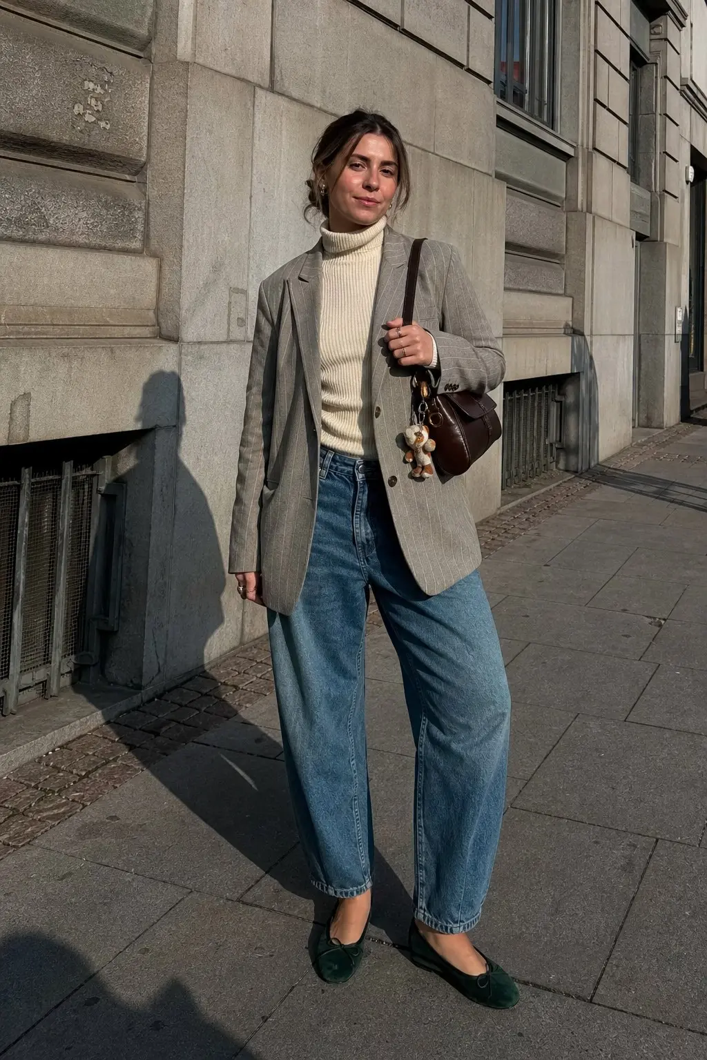 woman in grey pinstripe oversized blazer cream ribbed turtleneck barrel leg light wash blue jeans dark green velvet ballet flats chocolate brown structured top handle bag outfit 14