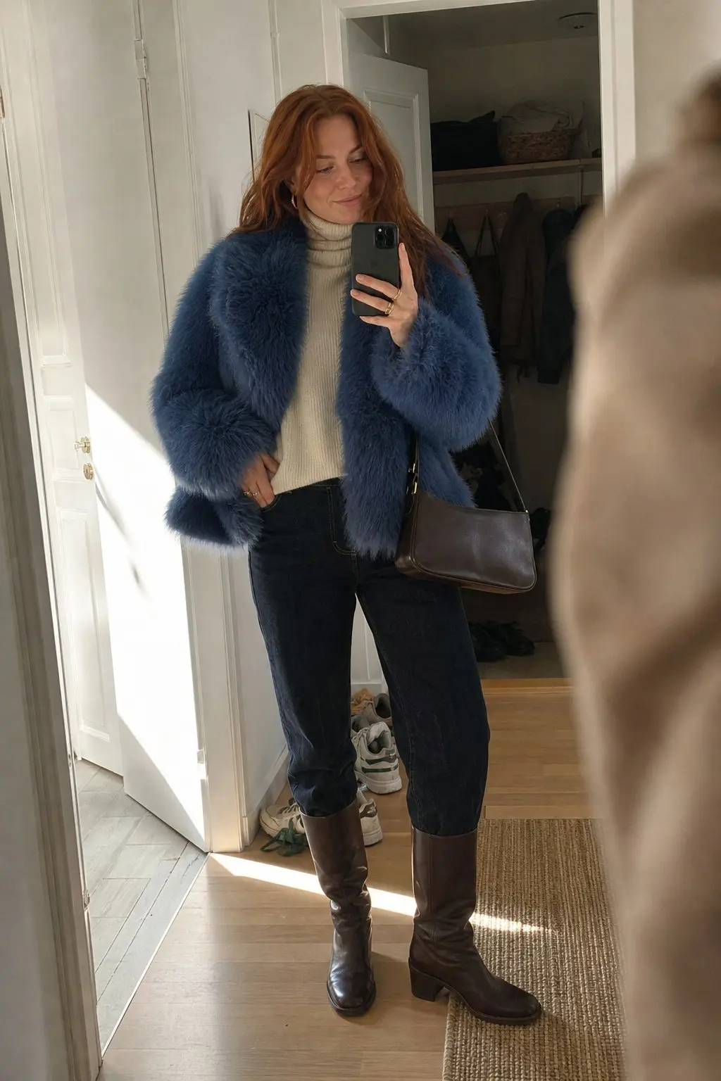 woman in cobalt blue faux fur coat cream turtleneck dark straight jeans tall brown leather boots dark brown leather shoulder bag gold ring outfit 17