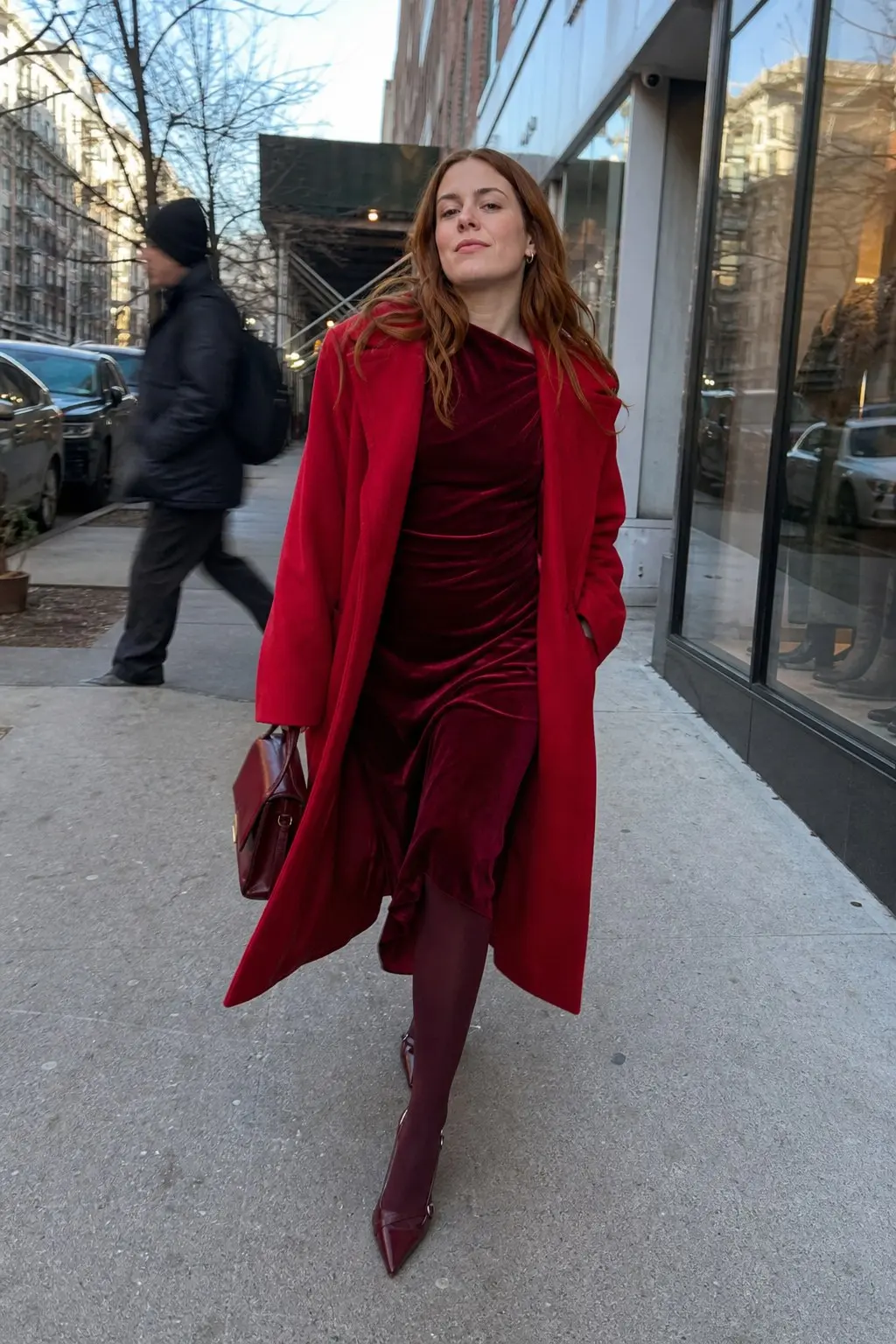 woman in dark red velvet ruched midi dress bright red wool longline coat burgundy opaque tights dark red pointed toe kitten heel boots small dark red top handle bag outfit 2