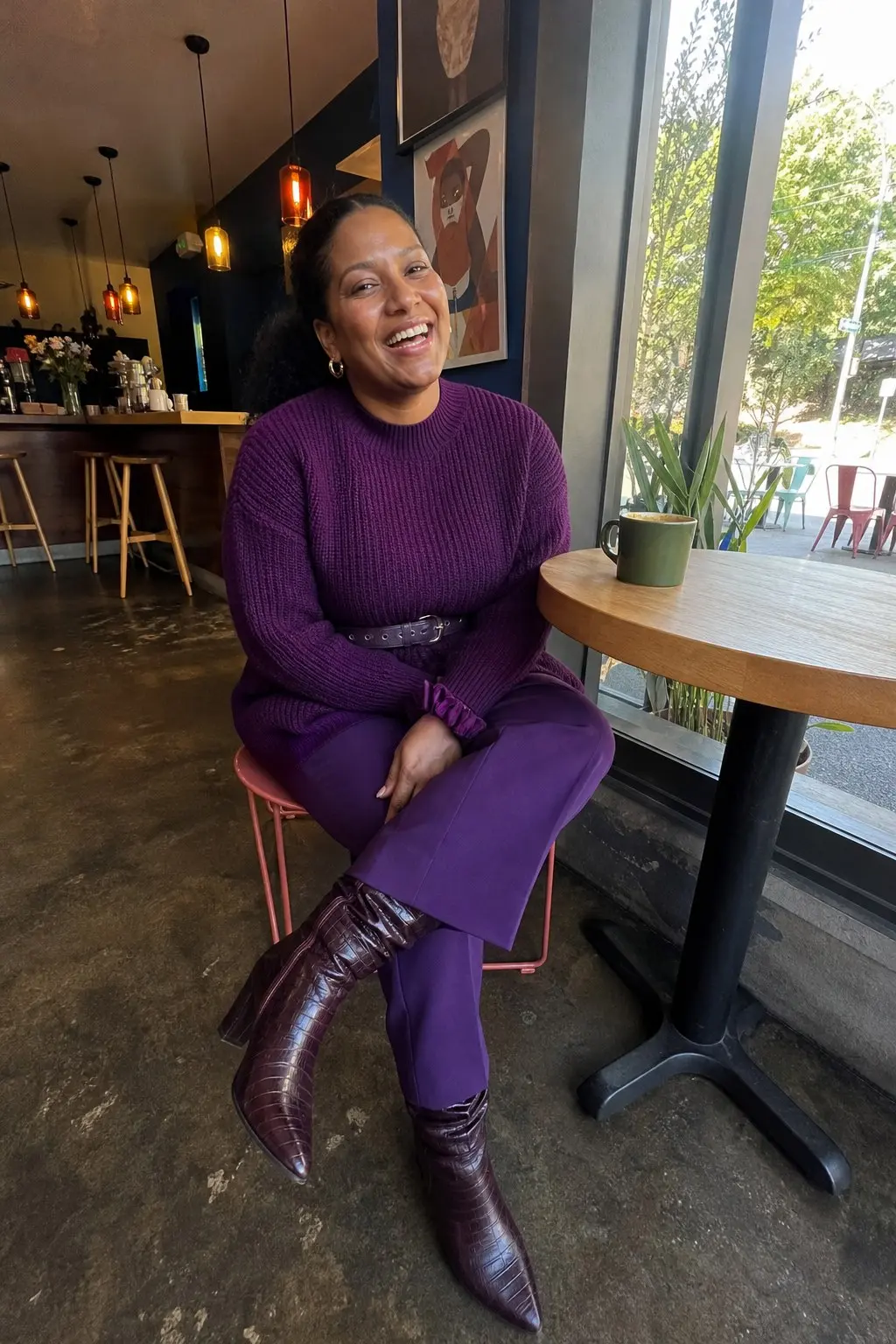 woman in deep purple chunky ribbed mock-neck sweater with black belt straight leg purple trousers dark brown croc-embossed knee-high boots gold hoop earrings outfit 3