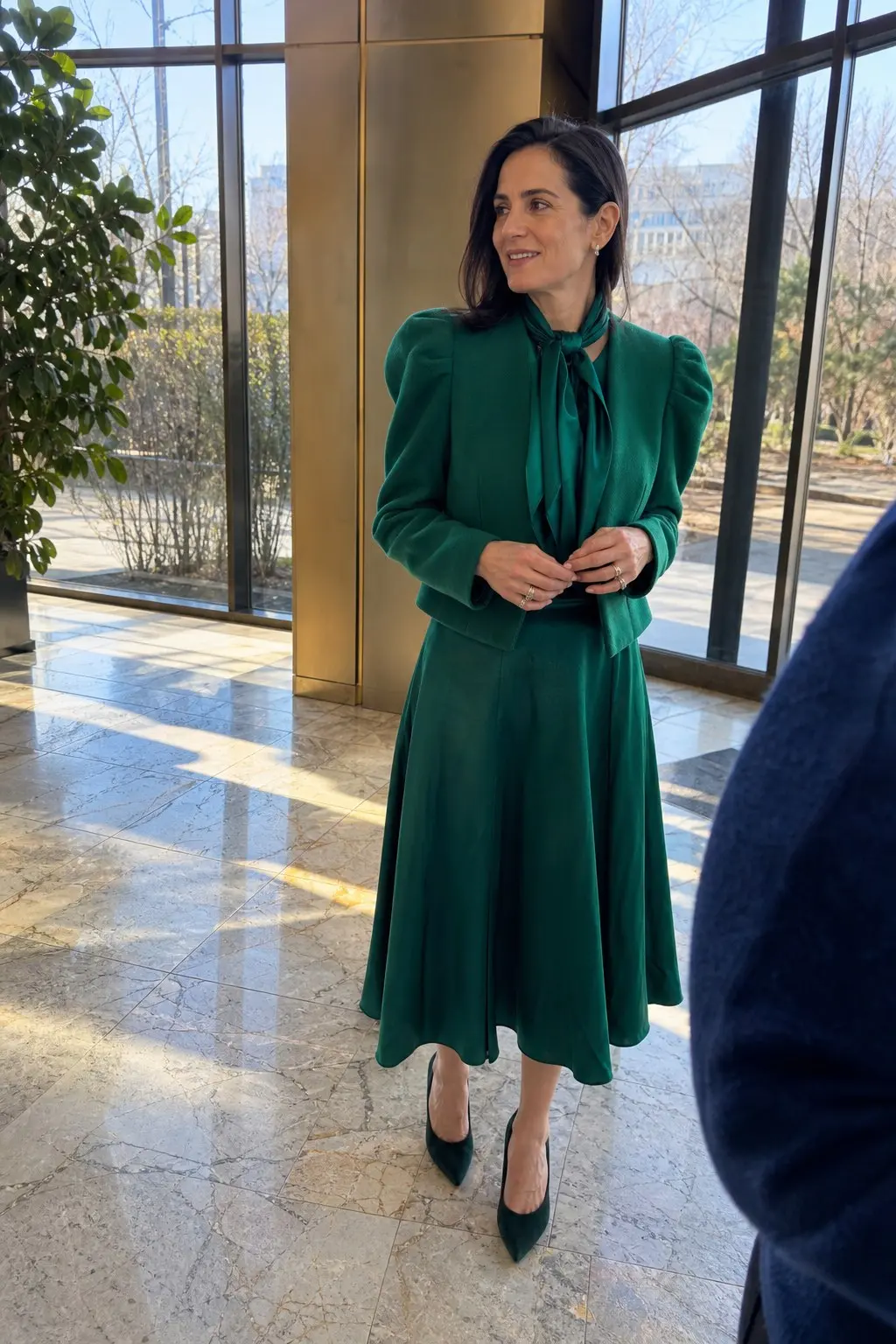 woman in emerald green puff-sleeve cropped blazer matching green tie-neck blouse full flared midi skirt dark green suede pointed pumps outfit 4