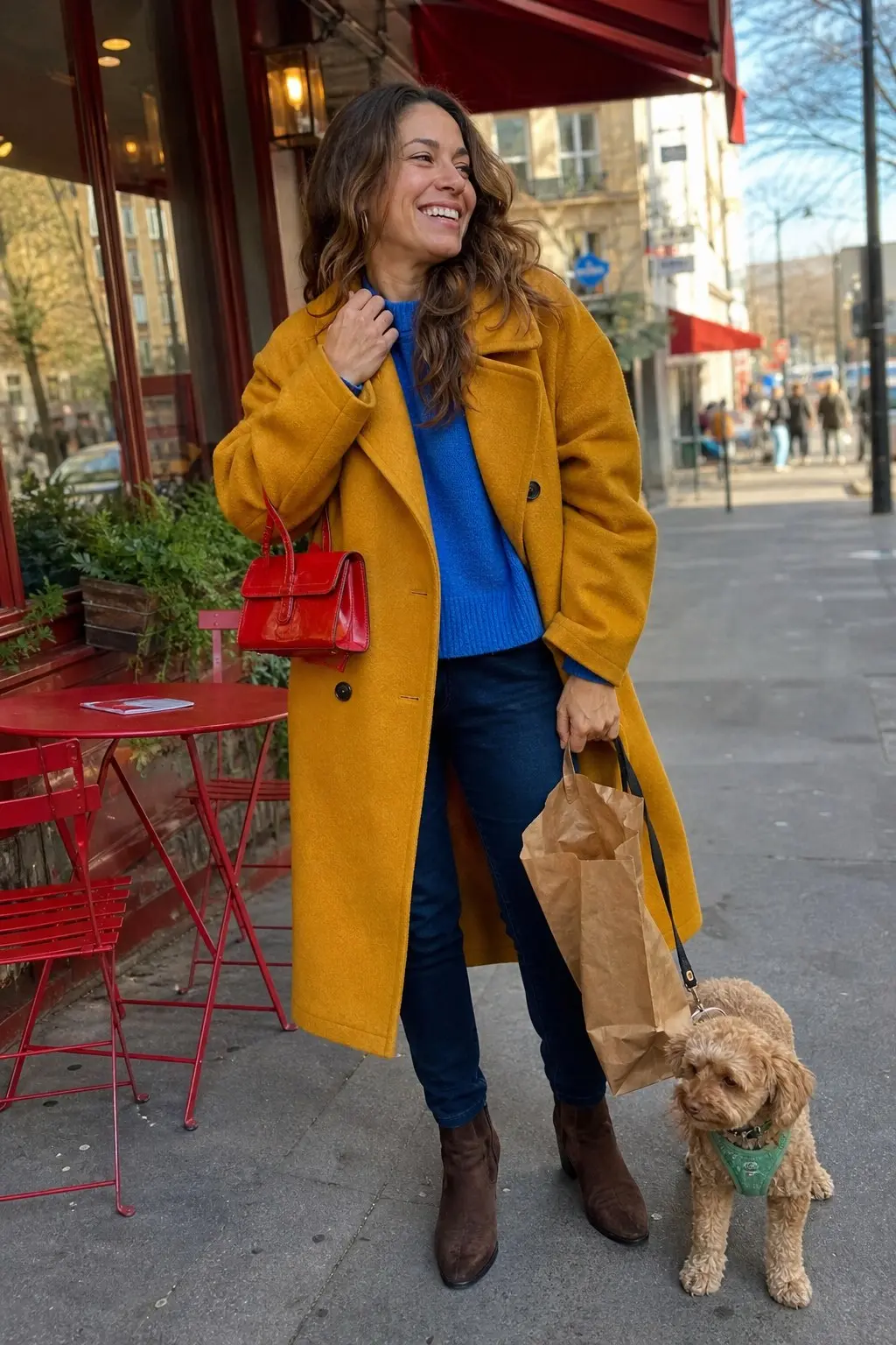 woman in mustard yellow wool longline coat cobalt blue chunky knit sweater slim dark indigo jeans brown suede ankle boots small red patent structured top handle bag outfit 7