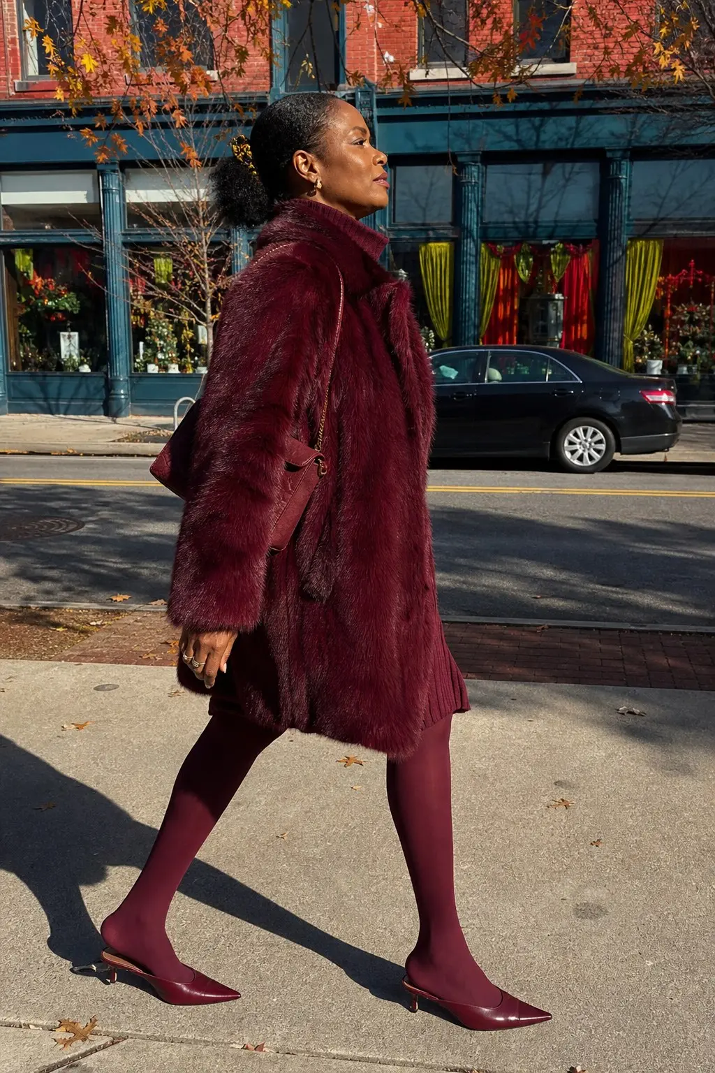 woman in burgundy faux fur coat burgundy ribbed knit mini dress burgundy opaque tights burgundy pointed toe kitten heel mules gold chain strap mini bag gold earrings outfit 10
