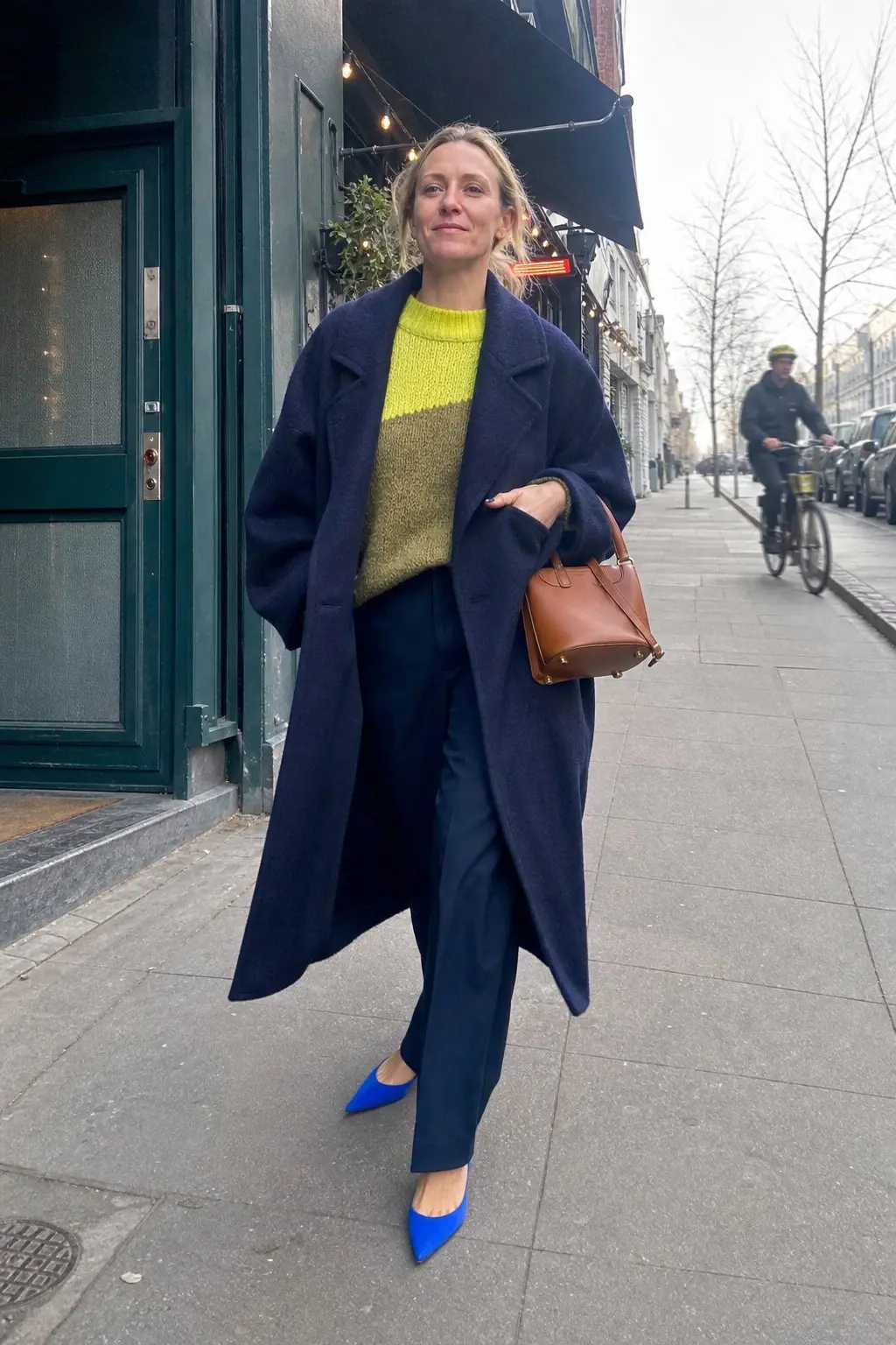 woman in navy longline oversized wool coat yellow chartreuse color block knit sweater navy wide leg trousers cobalt blue pointed slingback pumps tan brown structured leather top handle bag outfit 15