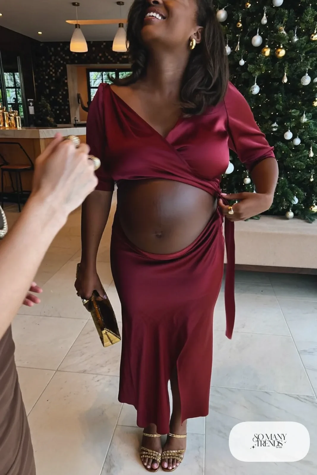 pregnant woman in red satin wrap dress, gold strappy mules, gold clutch, stacked gold rings, outfit 7