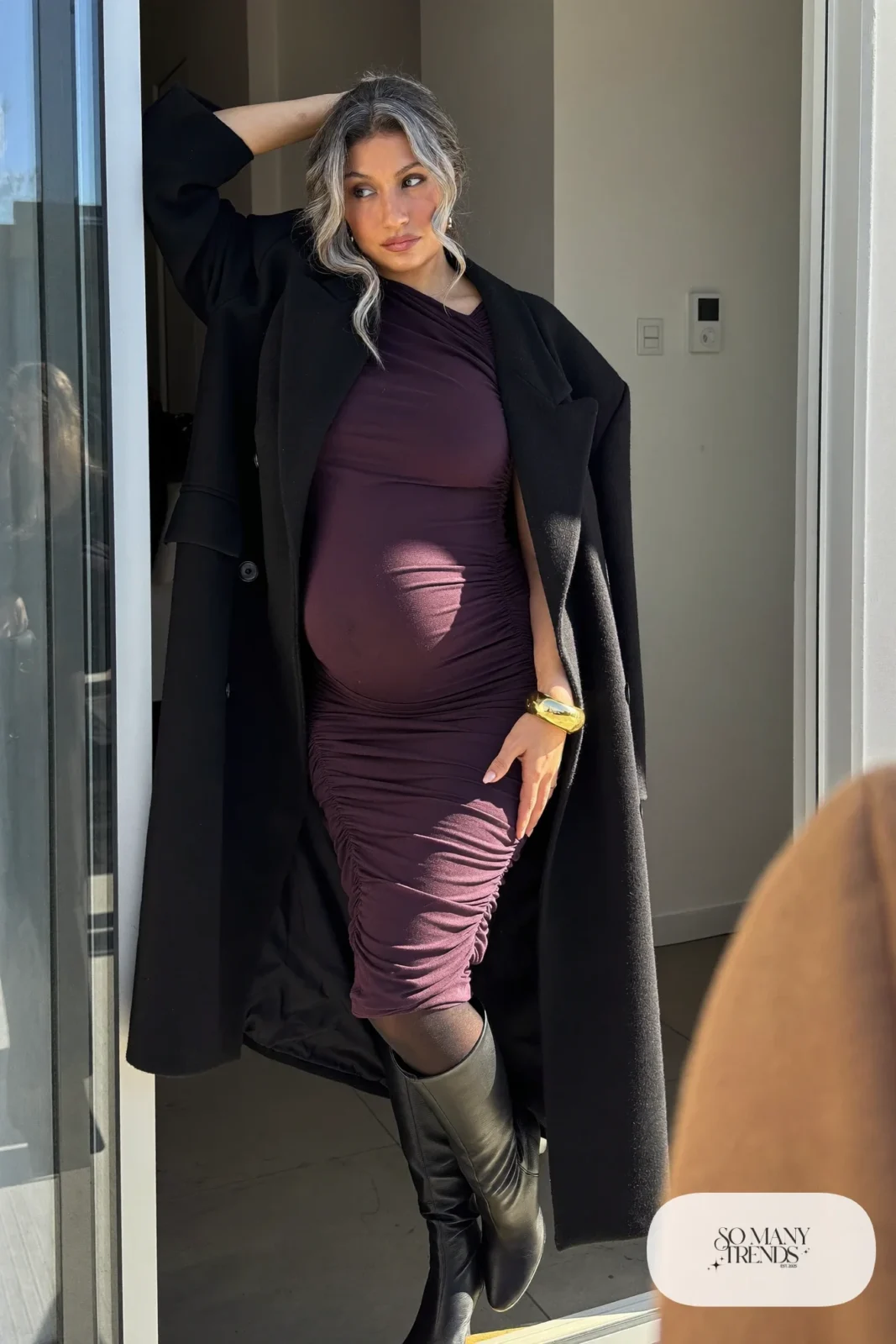 pregnant woman in deep plum ruched jersey midi dress, long black wool coat open, black tights, black knee high block heel boots, gold bangle, outfit 13