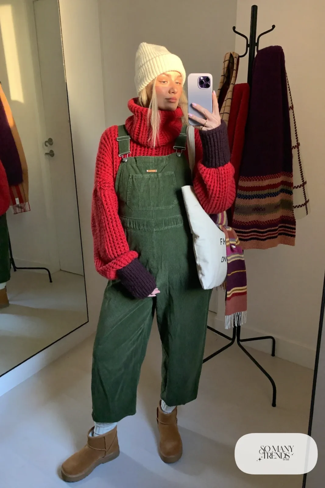 pregnant woman in olive green corduroy maternity overalls, cranberry red chunky turtleneck, caramel lug sole ankle boots, cream ribbed socks showing, cream knit beanie, canvas tote with striped scarf, outfit 21