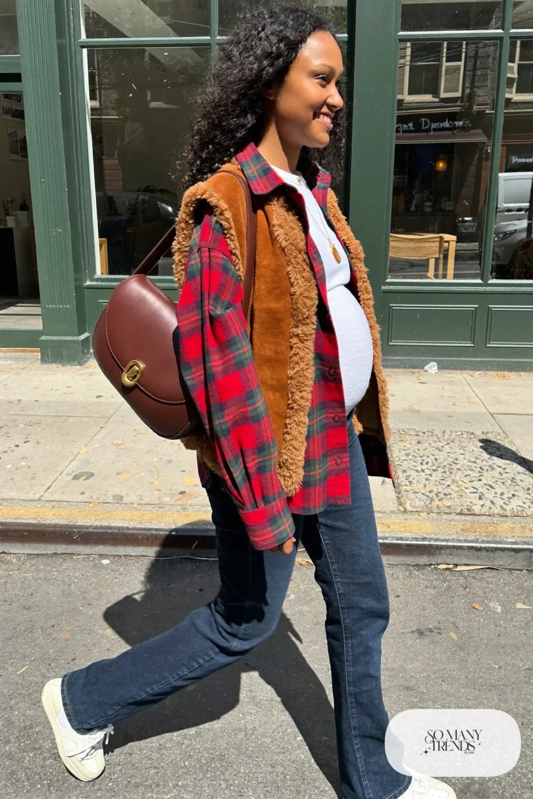 pregnant woman in dark wash maternity straight jeans, white long sleeve tee, red green plaid flannel overshirt open, camel shearling vest, white sneakers, brown leather crossbody, gold pendant necklace, outfit 22