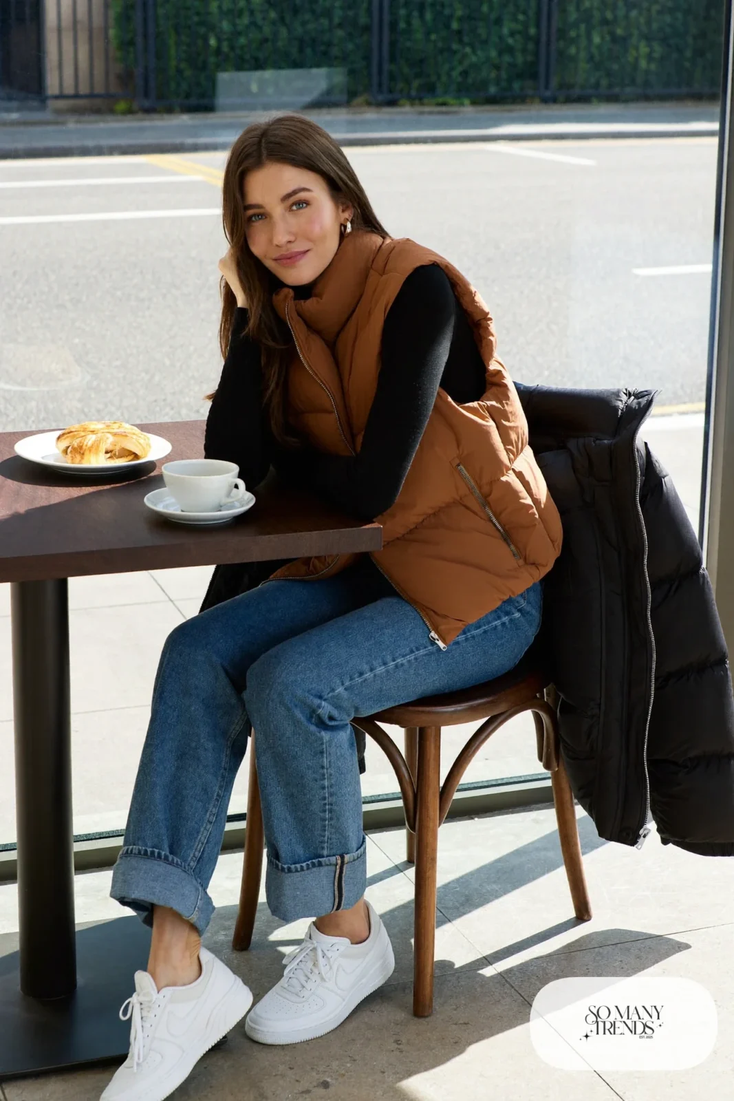 camel vest black long sleeve top straight blue jeans white sneakers puffer jacket outfit 28