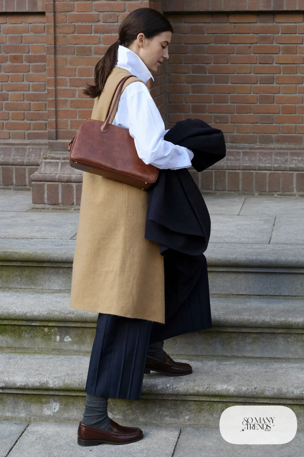camel knit vest, white shirt with collar out, navy pleated pants, brown penny loafers, gray socks, outfit 10