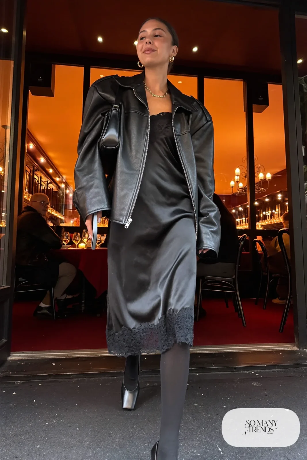 black lace trim slip dress oversized black leather moto jacket black tights ankle-height block heel pumps small shoulder bag outfit 1