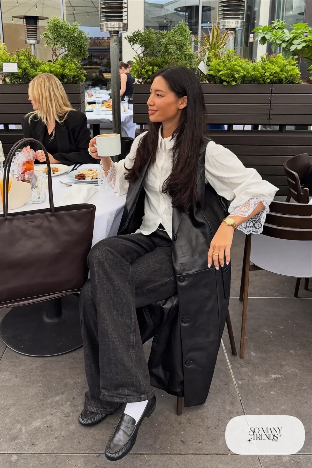 black faux leather longline vest white lace cuff blouse dark straight jeans black loafers gold watch tote bag outfit 23