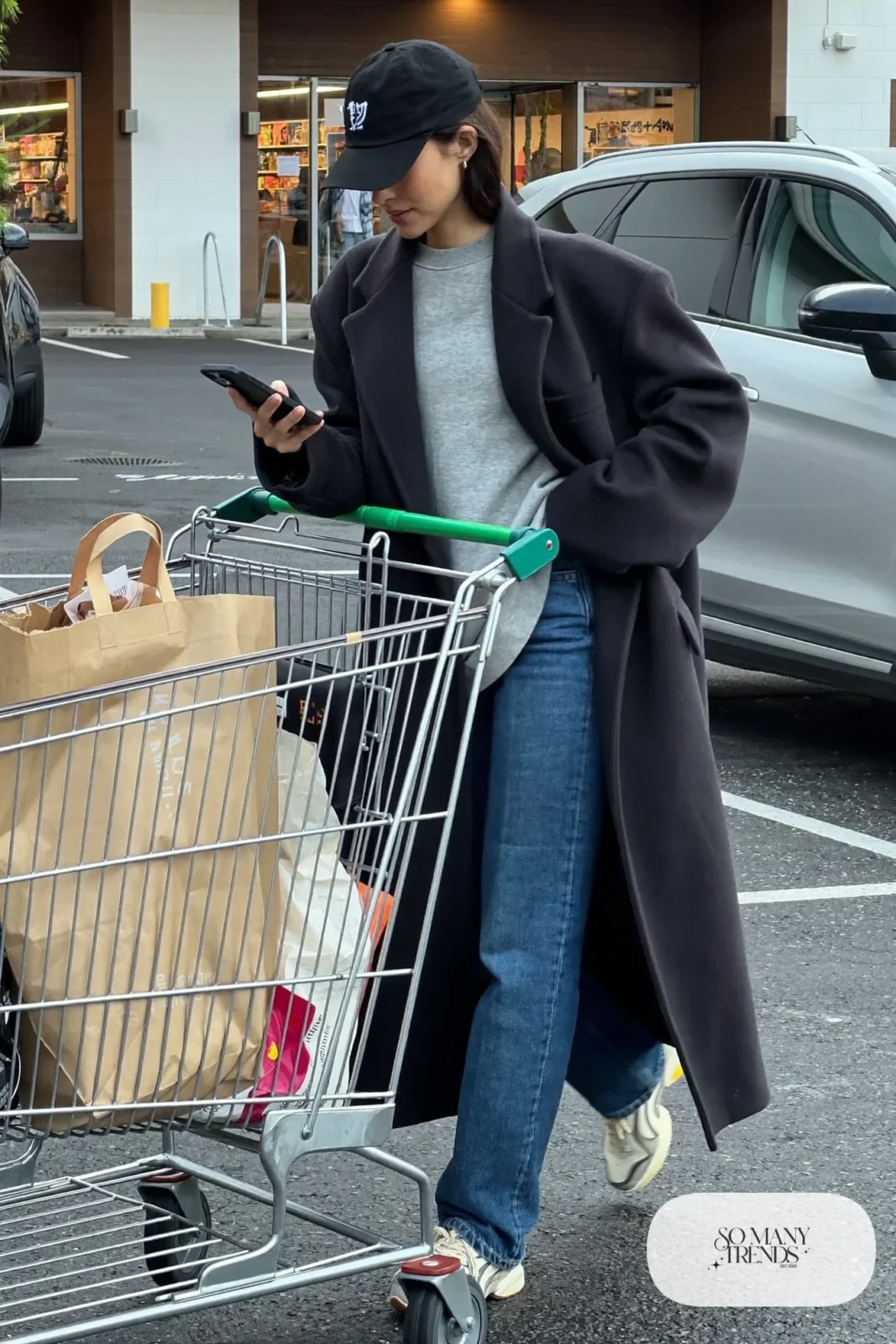 black long wool coat gray crewneck sweatshirt blue straight jeans chunky white sneakers baseball cap outfit 14