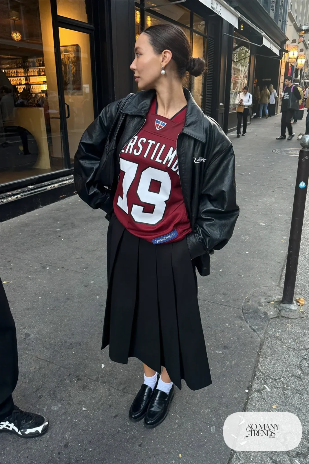 burgundy football jersey tucked black pleated midi skirt black leather jacket loafers socks pearl studs outfit 15