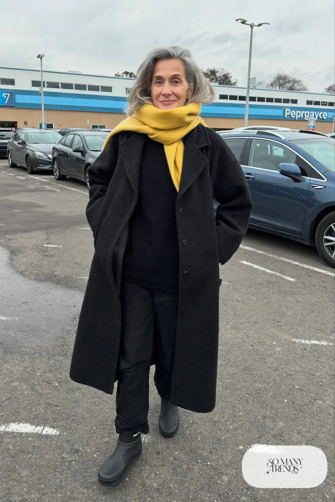 woman over 60 in black wool coat black sweater black pants mustard yellow scarf waterproof boots outfit 5