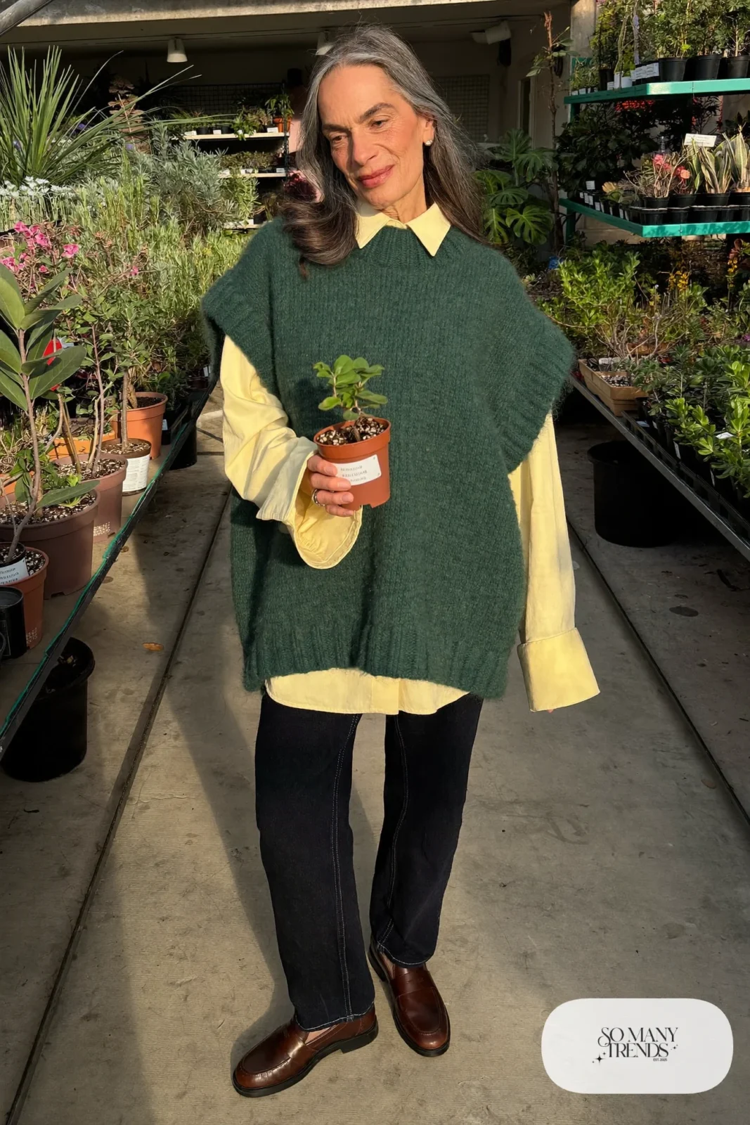 woman over 60 in forest green knit vest cream collared shirt dark jeans brown loafers socks outfit 9