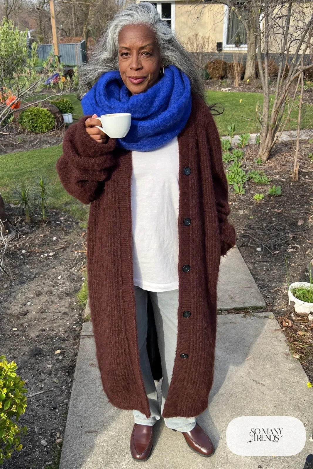 woman over 60 in chunky brown cardigan white tee gray pants cobalt blue scarf loafers outfit 12