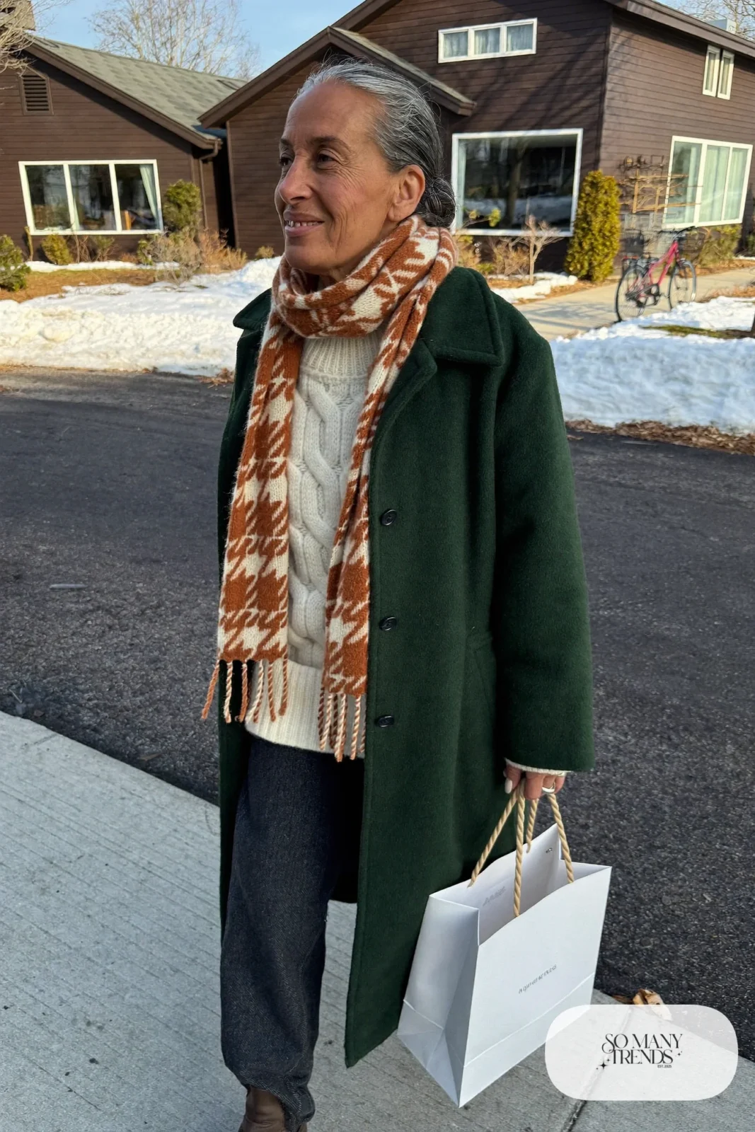 woman over 60 in forest green wool coat cream knit charcoal pants brown boots patterned scarf outfit 24