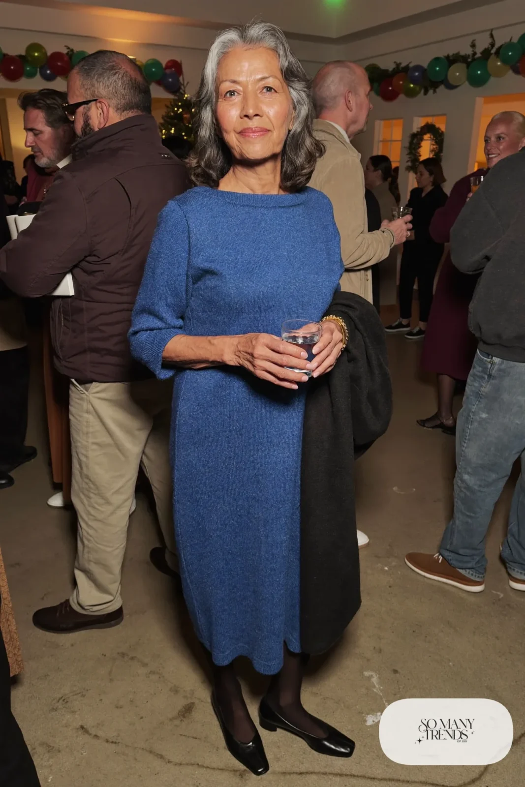 woman over 60 in cobalt blue knit midi dress black tights block heel pumps black wool wrap gold bracelet outfit 30