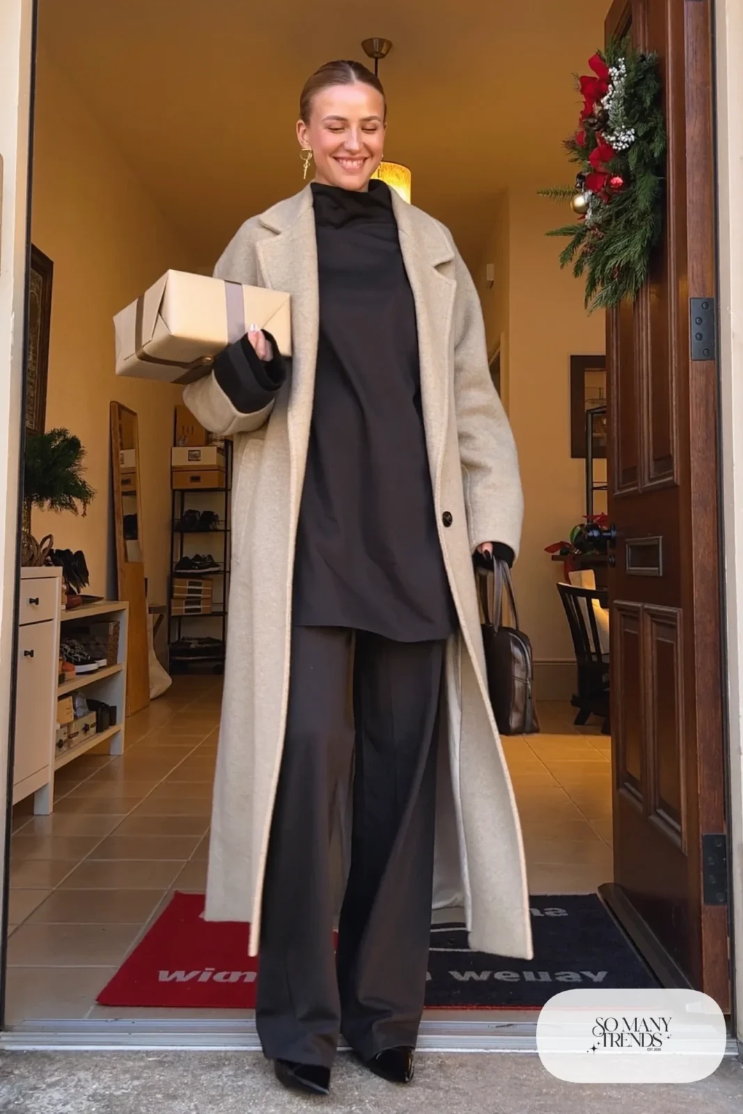 black wide-leg crepe jumpsuit long camel coat gold earrings black pointed flats outfit 21