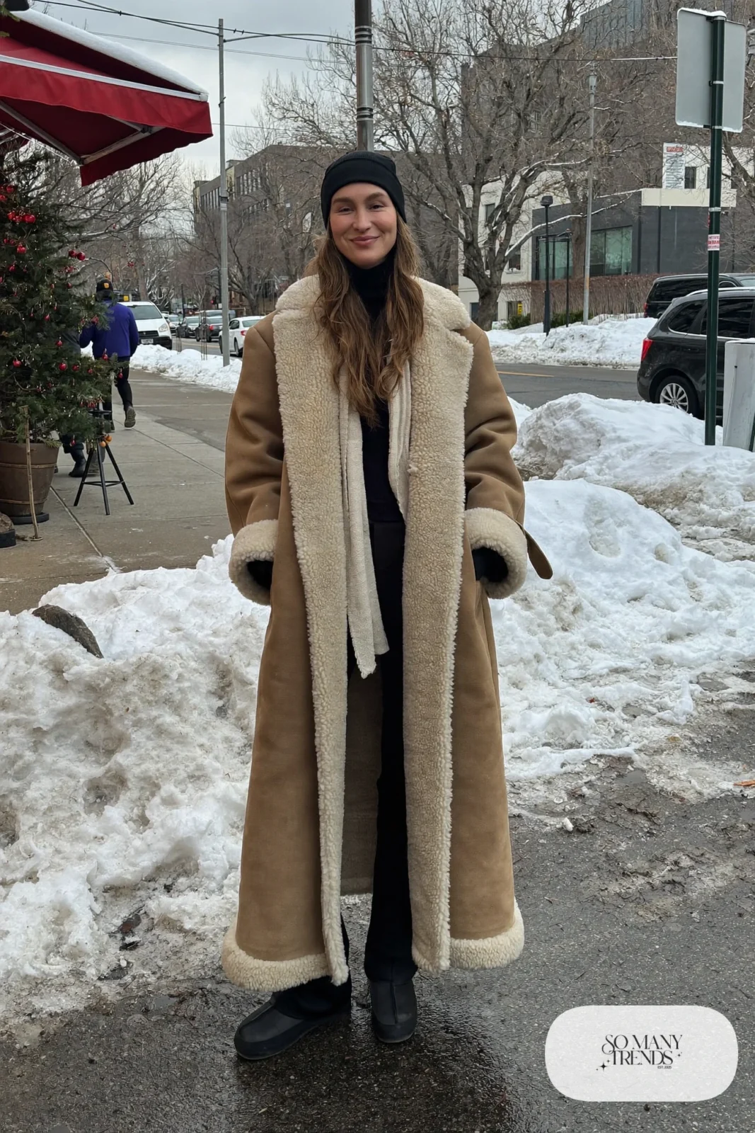 long oversized tan shearling coat black turtleneck black straight pants black boots black beanie january outfit 30