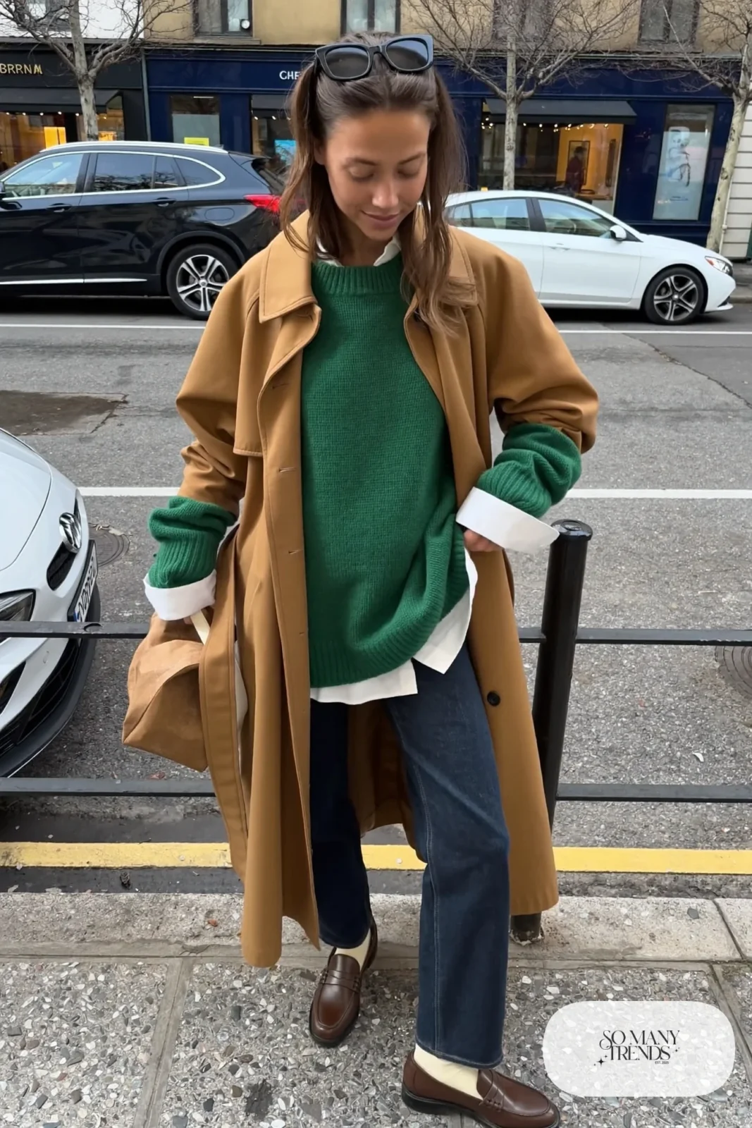 Camel trench coat belted over forest green sweater and white collared shirt, dark straight jeans, loafers, winter outfit 3